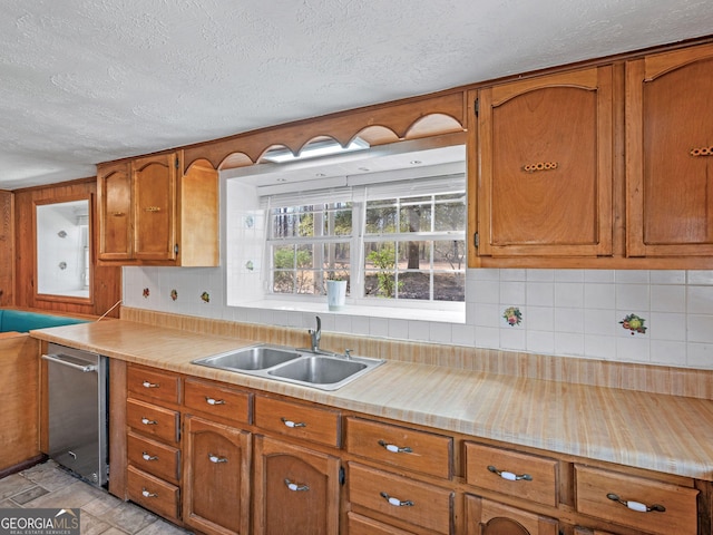 kitchen featuring tasteful backsplash, brown cabinets, a sink, and light countertops