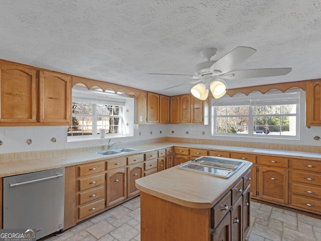 kitchen featuring stone tile floors, dishwasher, stovetop with downdraft, light countertops, and a sink