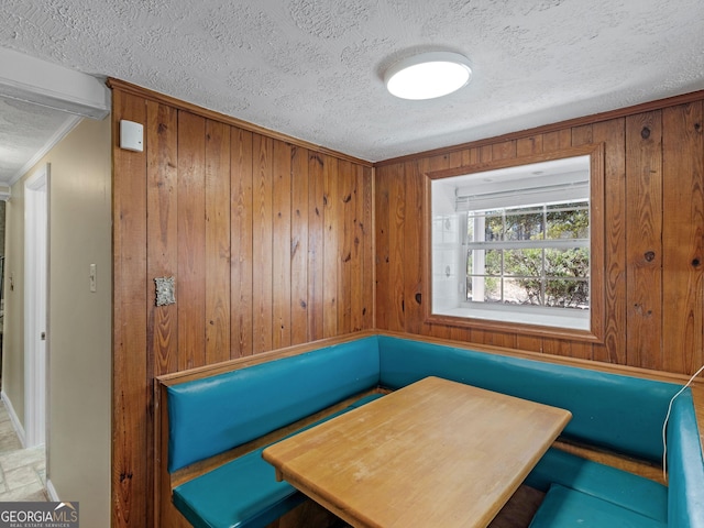 dining area with wood walls, crown molding, and a textured ceiling