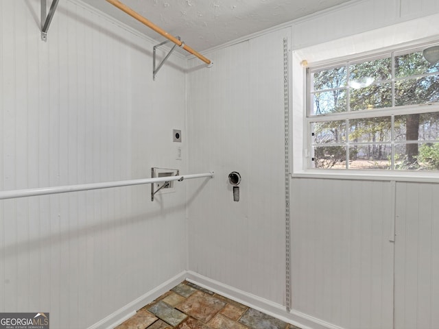 laundry room featuring a textured ceiling, laundry area, stone finish flooring, and hookup for an electric dryer