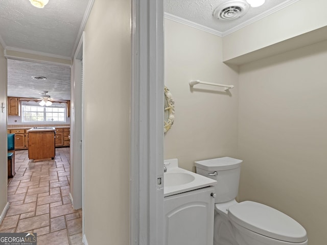 bathroom featuring toilet, visible vents, a textured ceiling, and ornamental molding