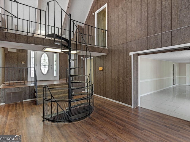 interior space featuring stairway, a towering ceiling, baseboards, and wood finished floors