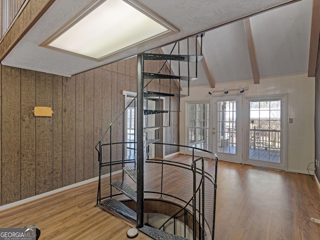 stairway featuring wooden walls, visible vents, baseboards, lofted ceiling with beams, and wood finished floors