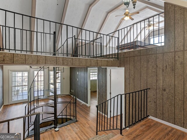 stairs with baseboards, ceiling fan, high vaulted ceiling, and wood finished floors