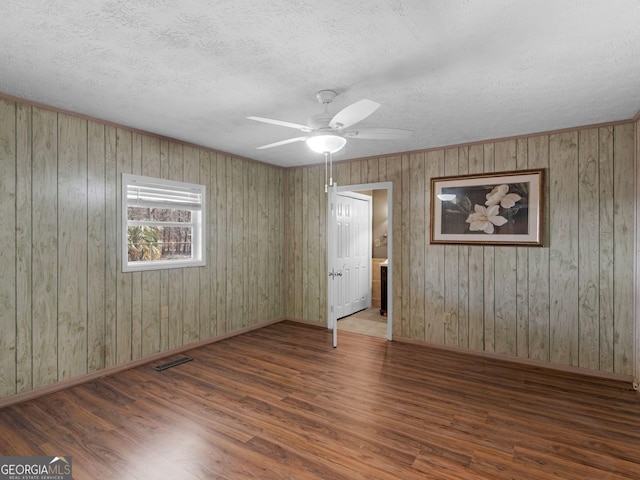 spare room with baseboards, a textured ceiling, visible vents, and wood finished floors