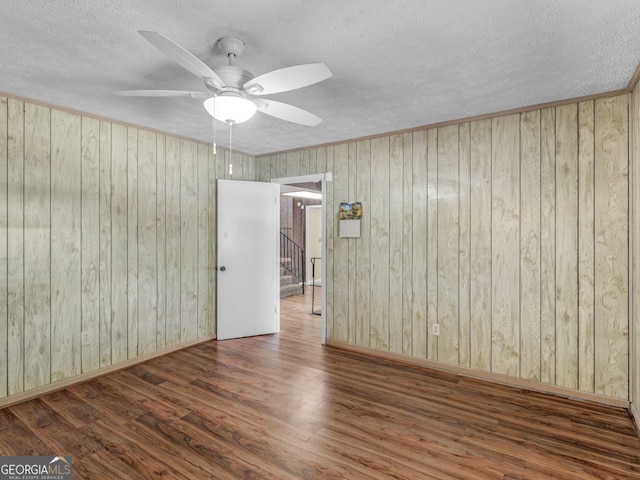 empty room featuring stairway, ceiling fan, a textured ceiling, wood finished floors, and baseboards