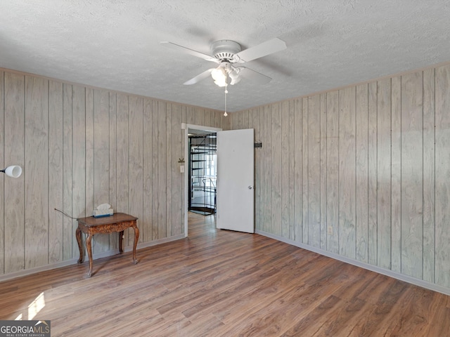 unfurnished room featuring a textured ceiling, ceiling fan, wood finished floors, and baseboards