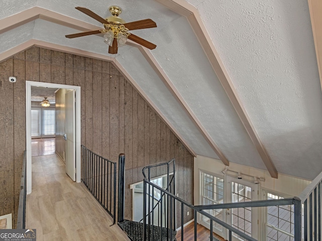 additional living space featuring vaulted ceiling, light wood finished floors, a textured ceiling, and wood walls