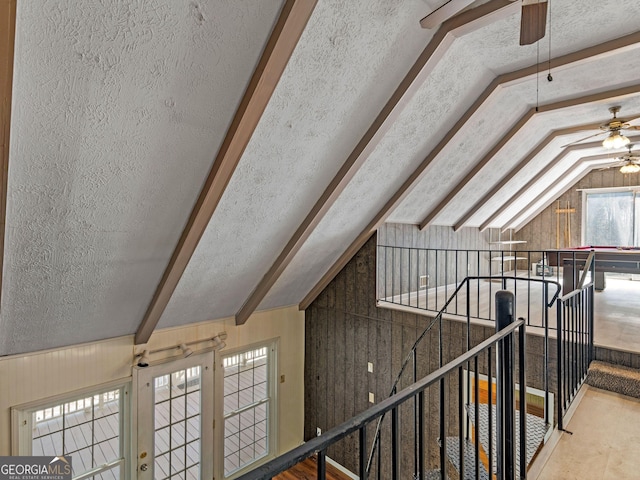 additional living space featuring lofted ceiling, wood walls, ceiling fan, and a textured ceiling