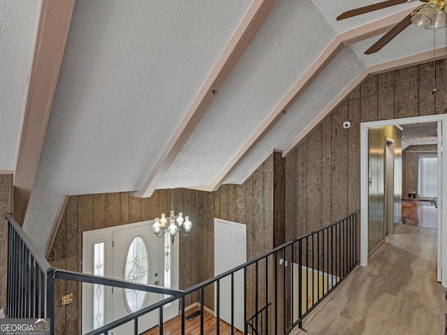 interior space with a textured ceiling, a chandelier, wood finished floors, vaulted ceiling, and stairs