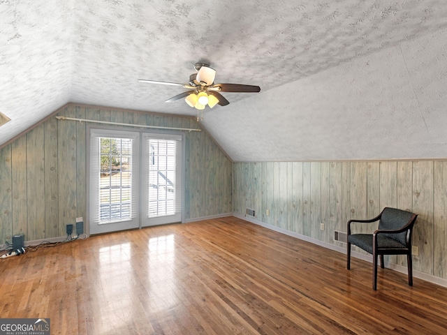 bonus room featuring lofted ceiling, a ceiling fan, a textured ceiling, baseboards, and hardwood / wood-style flooring