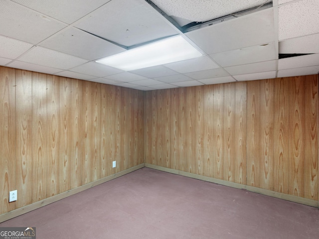 spare room featuring concrete flooring, a paneled ceiling, and wooden walls