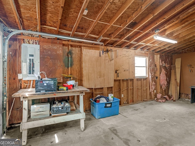 misc room with a garage, electric panel, and a workshop area