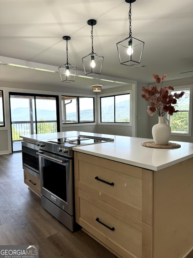 kitchen featuring light countertops, stainless steel range with electric cooktop, dark wood finished floors, and hanging light fixtures