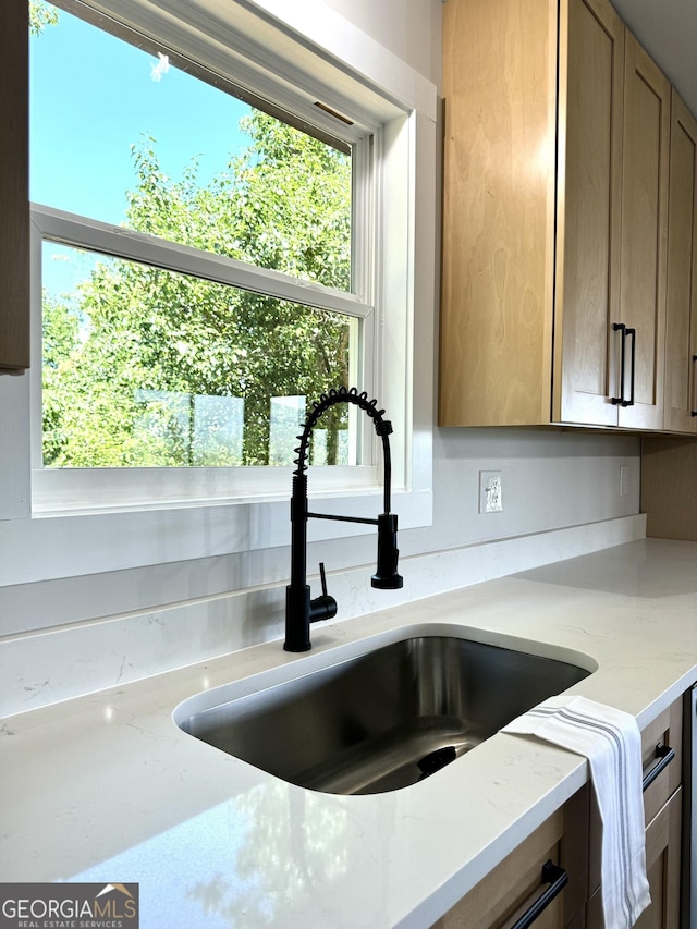 interior details featuring light stone counters and a sink