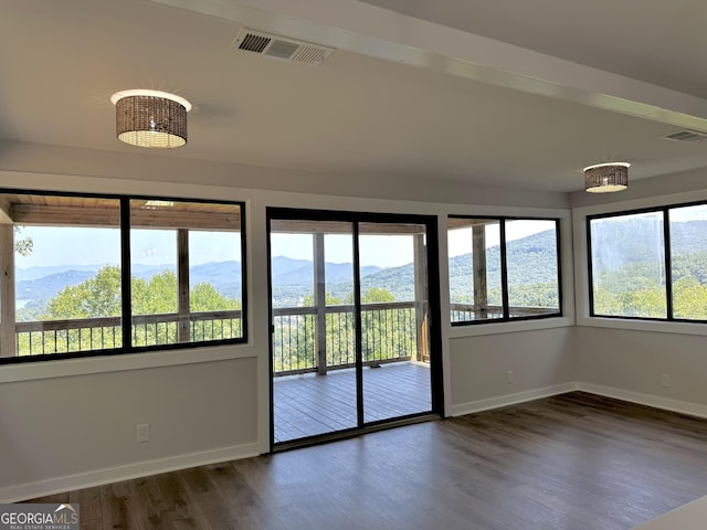 empty room featuring visible vents, a mountain view, and wood finished floors