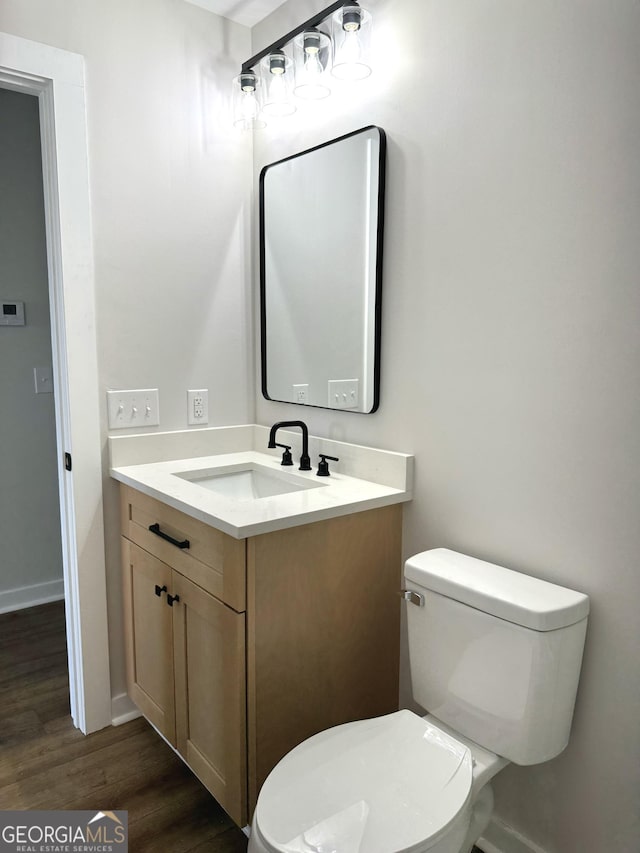 bathroom featuring baseboards, vanity, toilet, and wood finished floors