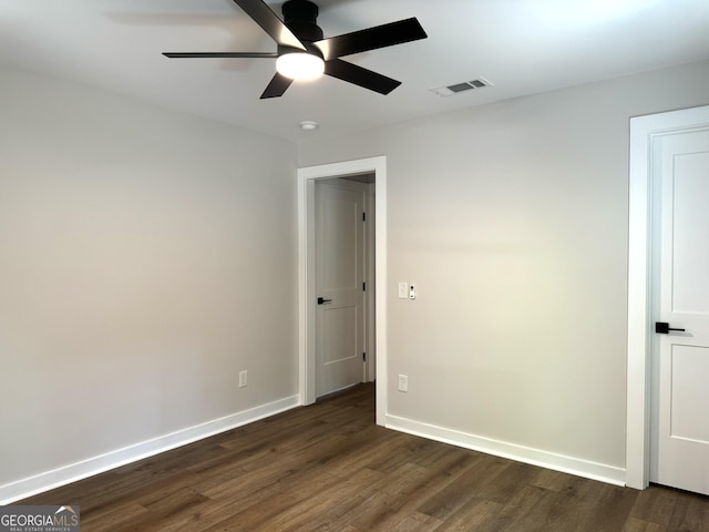 unfurnished room with dark wood-style floors, a ceiling fan, visible vents, and baseboards