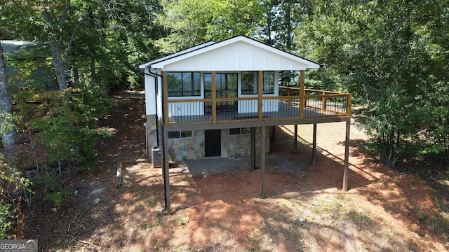 rear view of property featuring stone siding, board and batten siding, and a wooden deck