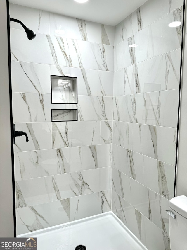 bathroom featuring toilet and tiled shower