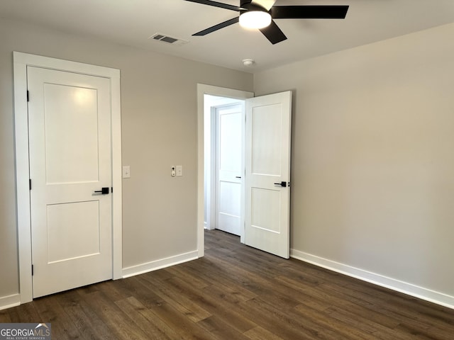 unfurnished bedroom with dark wood-style floors, visible vents, baseboards, and a ceiling fan