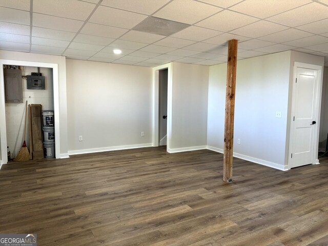 finished basement with electric panel, dark wood finished floors, a drop ceiling, and baseboards