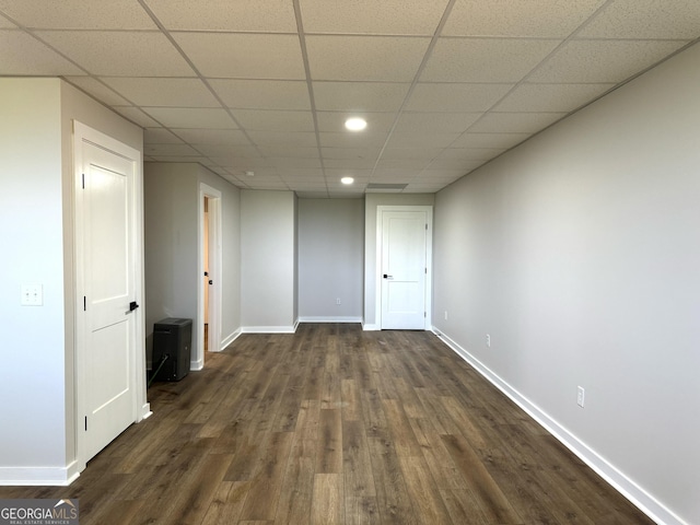 interior space featuring a paneled ceiling, baseboards, and dark wood-type flooring