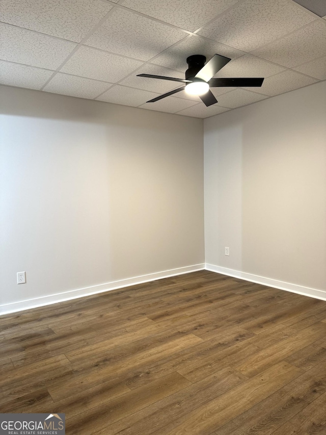 empty room with a paneled ceiling, baseboards, dark wood finished floors, and a ceiling fan