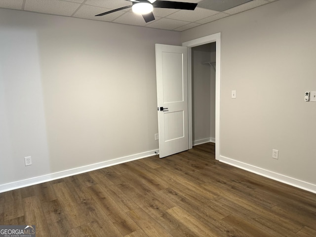 unfurnished room with a drop ceiling, dark wood finished floors, a ceiling fan, and baseboards