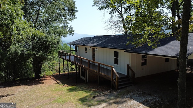 back of house featuring a deck and roof with shingles