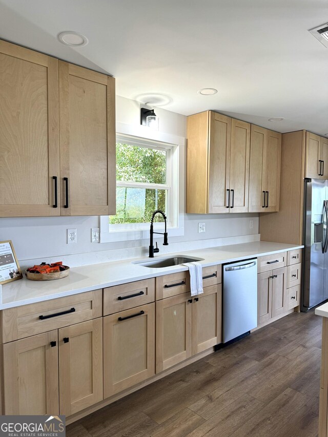 kitchen featuring dark wood-style floors, stainless steel appliances, light countertops, light brown cabinets, and a sink