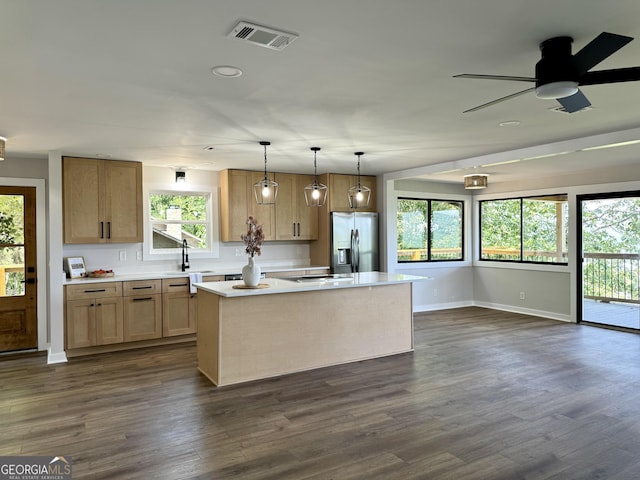 kitchen with dark wood finished floors, light countertops, visible vents, a kitchen island, and stainless steel fridge