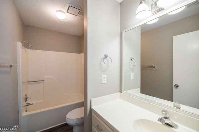 full bathroom with visible vents, shower / bathing tub combination, toilet, vanity, and a textured ceiling