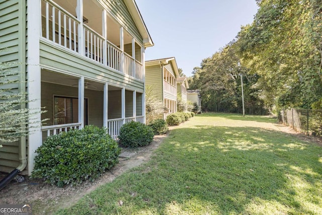 view of yard with a balcony, ceiling fan, and fence