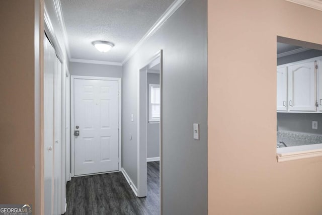 hallway with a textured ceiling, ornamental molding, dark wood-style floors, and baseboards