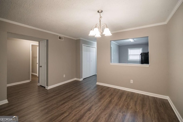 unfurnished room featuring baseboards, visible vents, dark wood-style floors, an inviting chandelier, and crown molding