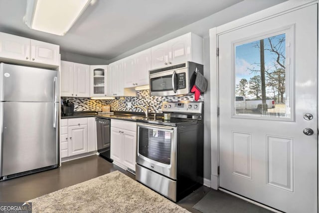 kitchen featuring glass insert cabinets, backsplash, stainless steel appliances, white cabinetry, and a sink