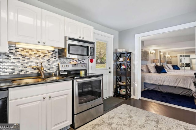 kitchen featuring stainless steel appliances, decorative backsplash, open floor plan, white cabinets, and a sink