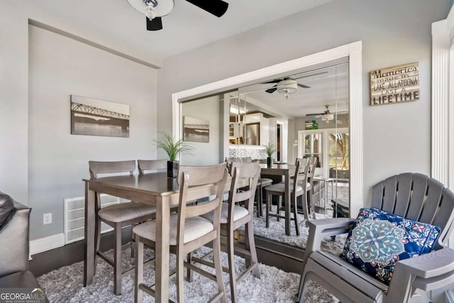 dining area with a ceiling fan, visible vents, baseboards, and wood finished floors