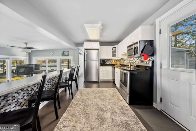 kitchen with stainless steel appliances, white cabinetry, glass insert cabinets, and backsplash