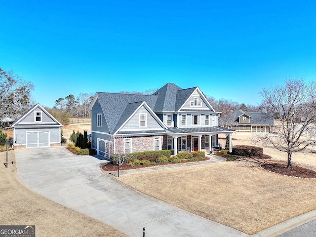 shingle-style home with a detached garage, covered porch, a standing seam roof, metal roof, and an outdoor structure