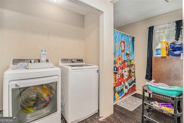 laundry area with laundry area, washing machine and dryer, a textured ceiling, and wood finished floors