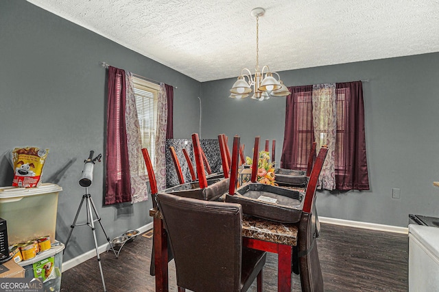 dining area with a textured ceiling, baseboards, a chandelier, and wood finished floors