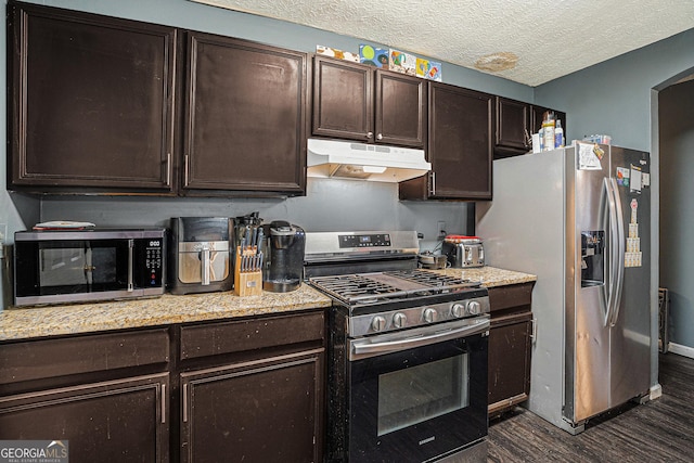 kitchen featuring arched walkways, stainless steel appliances, a textured ceiling, dark brown cabinets, and under cabinet range hood