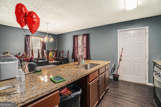 kitchen featuring a notable chandelier, a sink, light stone countertops, dark wood-style floors, and decorative light fixtures