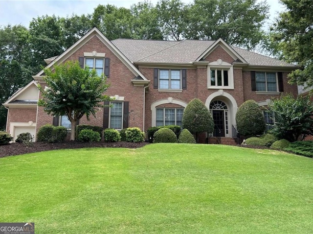 view of front of house featuring a front yard, a garage, and brick siding