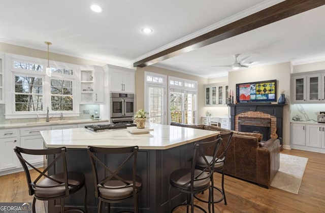 kitchen featuring a sink, open floor plan, appliances with stainless steel finishes, crown molding, and a brick fireplace