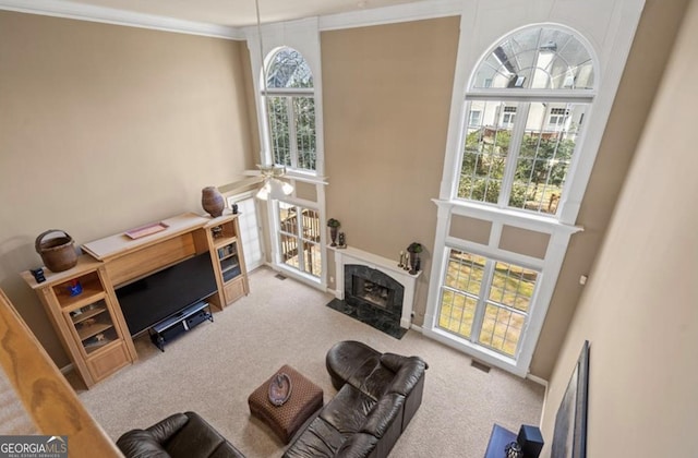 living area with crown molding, carpet flooring, plenty of natural light, and a high end fireplace