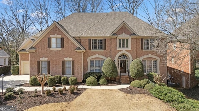 view of front of house with central air condition unit, brick siding, and roof with shingles