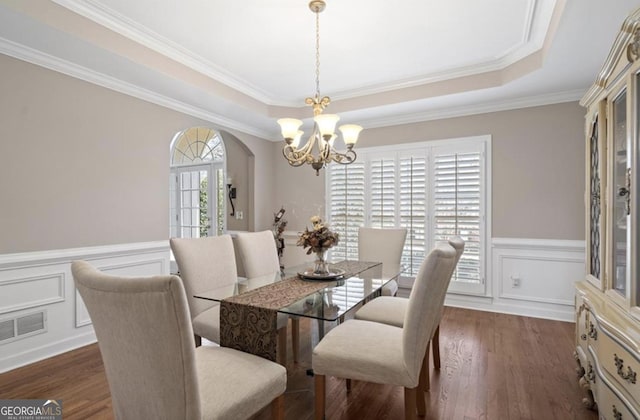 dining room featuring dark wood finished floors, a tray ceiling, arched walkways, and visible vents